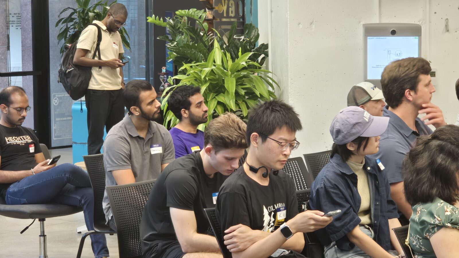 Attendees seated, some on laptops and phones