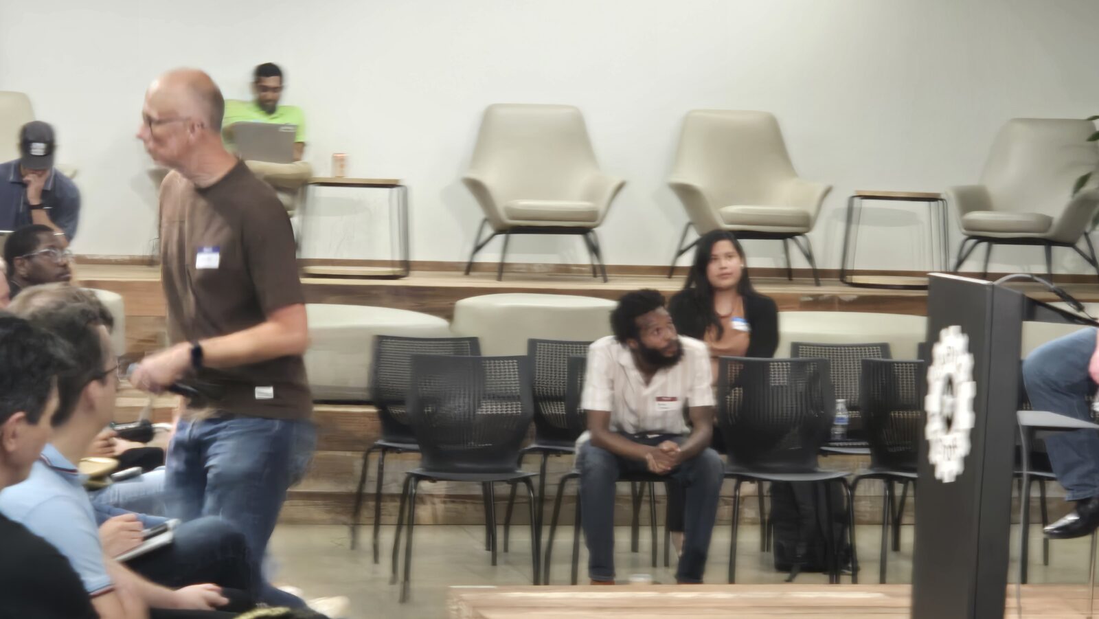 A speaker stands beside the lounge chairs near the stage