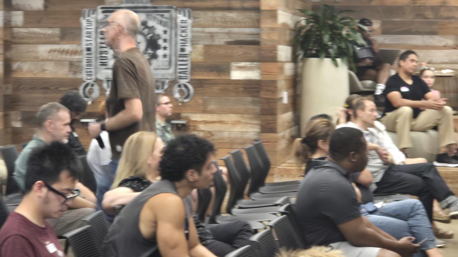 The audience against the reclaimed-wood wall with the Austin Startups emblem